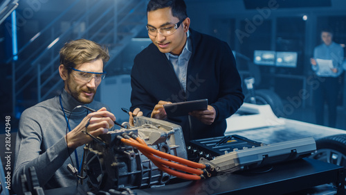 Cuadros en Lienzo Two Professional Automotive Engineers with a Tablet Computer and Inspection Tools are Having a Conversation While Testing an Electric Engine in a High Tech Laboratory with a Concept Car Chassis