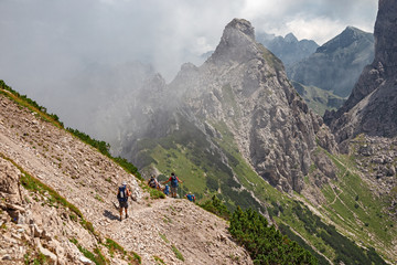 Wall Mural - some hikers go along an impassable rocky path, in view of the towers and peaks of the friulian dolom