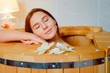 Woman having spa treatment and relaxing in wooden hot barrel sauna, cedar bathtub