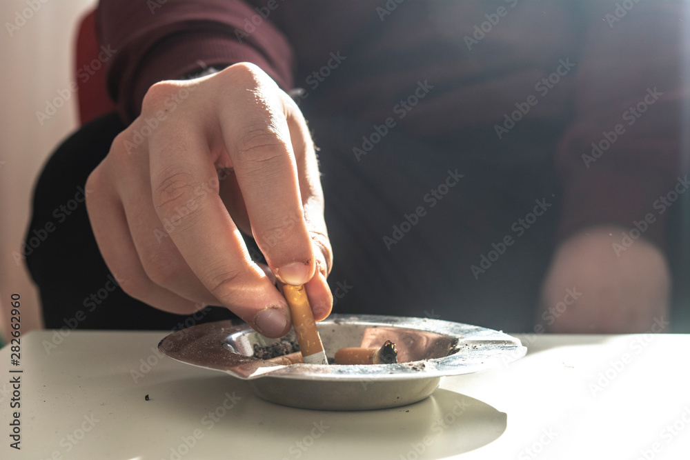 putting cigarette out Closeup of male hand putting out a cigarette in an ashtray Stock Photo