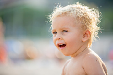 Canvas Print - Beautiful two years old toddler child, boy, playing with beach toys on the beach coast near water