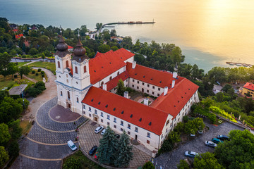 Wall Mural - Tihany, Hungary - Aerial drone view of the beautiful Benedictine Tihany Abbey (Tihanyi apatsag) on the northern shore of Lake Balaton with a golden sunrise at summer time