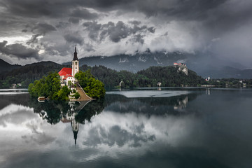 Wall Mural - Bled, Slovenia - Aerial view of beautiful Lake Bled (Blejsko Jezero) with the Pilgrimage Church of the Assumption of Maria and Bled Castle and Julian Alps at background on a dark misty morning