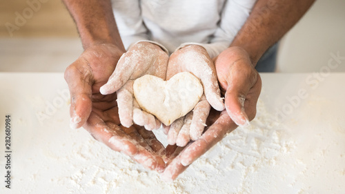 Fotomural Afro man hands holding child hands with heart shaped pastry