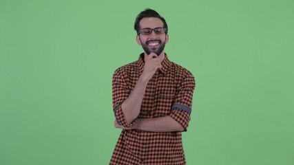 Wall Mural - Happy young bearded Persian hipster man thinking