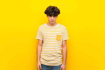 Young man over isolated yellow wall with sad and depressed expression