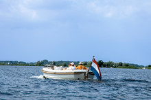 Tourists Enjoying Ride In White Luxury Motor Boat With Dutch Flag. Summer Vacation Or Boat Rent Theme.