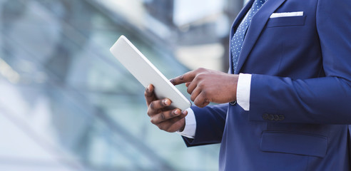 Black Businessman Using Tablet Computer Walking In City Center, Cropped