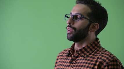 Wall Mural - Closeup profile view of happy young bearded Persian hipster man smiling