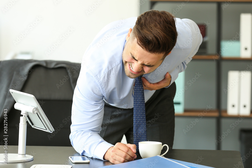 Young businessman having heart attack in office
