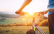 Man hands on the bike steering wheel close up image. Man with bike stay on the top of hill and enjoying the sunset.