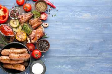 Tasty grilled meat with sausages and vegetables on wooden background