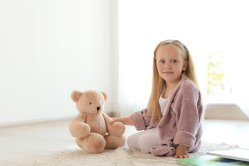 Wall Mural - Pretty little girl with book and teddy bear on floor in room