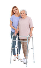 Canvas Print - Caretaker helping elderly woman with walking frame on white background