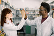 © sofiko14 - Two happy colleages pharmacists, African man and Caucasian woman working in drugstore, smiling. giving five and having fun.