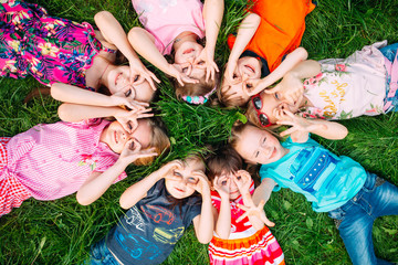 a group of children lying on the green grass in the park. the interaction of the children.