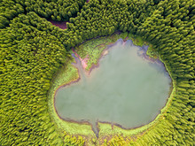Ghost Shaped Drone  Landscape. Top Down Aerial View Of A Small Pond In The Middle Of A Forest, Reflecting Clouds In The Sky. Bird View Of Canary Lagoon In Azores, Portugal.