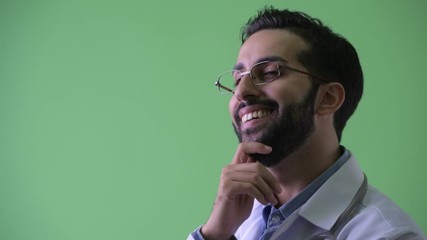 Wall Mural - Closeup profile view of happy young bearded Persian man doctor thinking