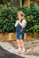 outdoor portrait of cute little 3-4 year old girl, wearing denim pinafore