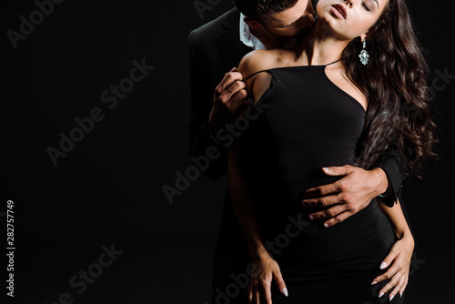 cropped view of passionate man kissing woman in dress isolated on black Obraz na płótnie