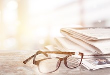 Newspapers With Reading Glasses On Background