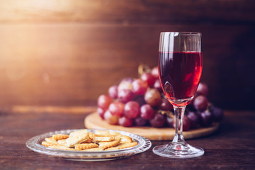 Wall Mural - Close-up of a wine glasses with bread in communion plate  over grape on wood plate against window light  on wooden table, christian background with copy space 