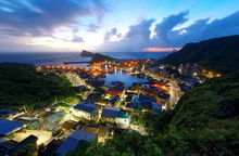 Sunrise Scenery Of A Fishing Village "Yehliu" On Northern Coast Of Taipei, Taiwan, With View Of A Highway Along The Beautiful Rocky Coastline & Lights Of The Village Houses Under Dramatic Dawning Sky