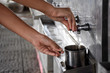 © Wararat - Women's hands are dropping water from a stainless steel dispenser, put in an old and dirty stainless steel cup