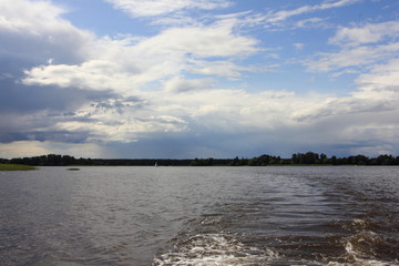 Wall Mural - Stormy blue sky with dark clouds over the water, beautiful river landscape on a summer day