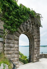 Sticker - old overgrown stone castle gate with a lake behind