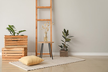 Table with wooden boxes and ladder near light wall in room