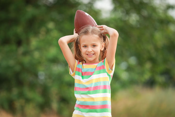 Poster - Portrait of cute little girl with rugby ball outdoors