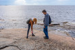 © Tatyana_Andreyeva - Middle aged man and young lady walking on northern lake shore in summer day. Tourists exploring ancient petroglyphs. Travelling and discovering distant places of Earth. Onega lake, Karelia, Russia