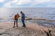 © Tatyana_Andreyeva - Middle aged man and young lady walking on northern lake shore in summer day. Tourists exploring ancient petroglyphs. Travelling and discovering distant places of Earth. Onega lake, Karelia, Russia