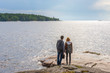 © Tatyana_Andreyeva - Middle aged man and young lady walking on northern lake shore in summer day. Tourists against picturesque landscape. Travelling and discovering distant places of Earth. Onega lake, Karelia, Russia