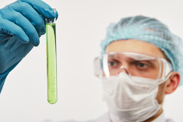 Doctor looking at green test tube