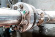 close-up view of the flange with bolts of a heavy metal joint on a pipe that transports liquid to an industrial plant