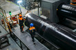 Workers examine new coated pipe in factory