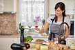© nenadaksic - Cute Caucasian brunette in apron standing in kitchen and adding salt in fresh delicious pasta. Preparation of italian food concept.