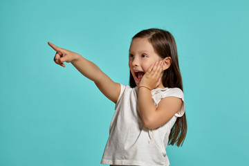 Close-up studio shot of beautiful brunette little girl posing against a blue background.