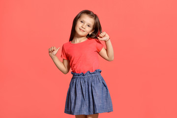 Close-up studio shot of beautiful brunette little girl posing against a blue background.