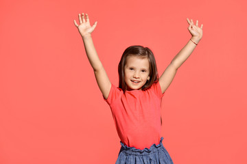 Close-up studio shot of beautiful brunette little girl posing against a blue background.