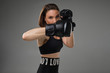 © nazarovsergey - Athletic woman in boxing gloves is practicing karate in studio.