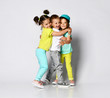 © FAB.1 - Studio portrait of children on a light background: full body shot of three children in bright clothes, two girls and one boy. Triplets, brother and sisters. hugging on camera.