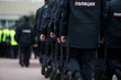 Russian police officers patrolling the street, rear view. Police officer holding a metal detector, security check.
