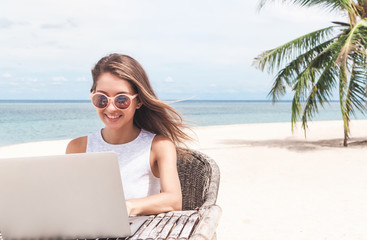 Young woman using laptop computer on a beach. Freelance  concept