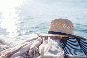 Wall Mural - Straw hat and other things of a traveler against the background of the sea in sunny glare. Vacations, rest.