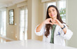© Krakenimages.com - Young woman wearing medical coat at the clinic as therapist or doctor smiling in love showing heart symbol and shape with hands. Romantic concept.