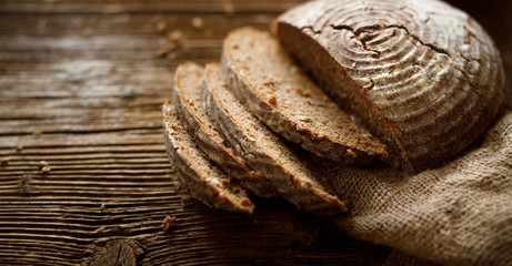 Bread,  traditional spelled sourdough bread cut into slices on a rustic wooden background, close-up, top view, copy space. Concept of traditional leavened bread baking methods