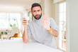 © Krakenimages.com - Handsome hispanic man drinking a cup of coffee with open hand doing stop sign with serious and confident expression, defense gesture
